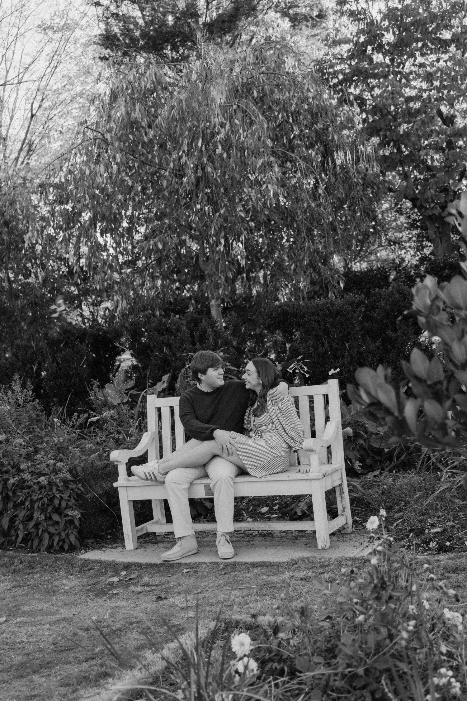 A sequence of black and white photos shows someone reclining and stretching out on a white garden bench.