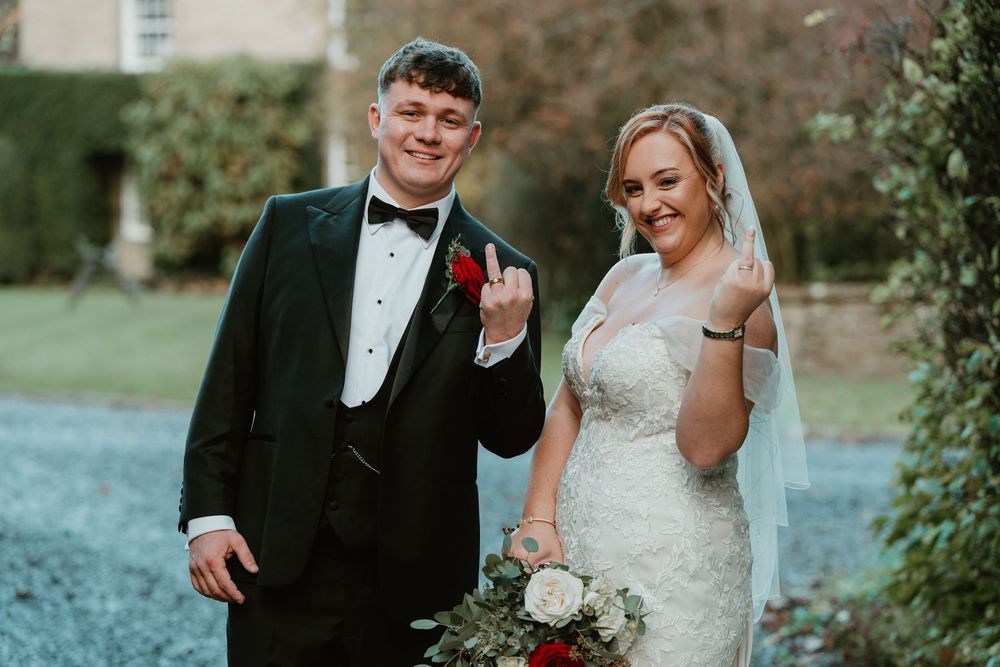A wedding couple shares joyful moments together in an outdoor garden setting with lush greenery.