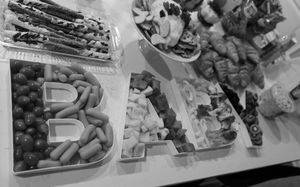 Black and white photo of a baby shower charcuterie board arranged in letter shapes.