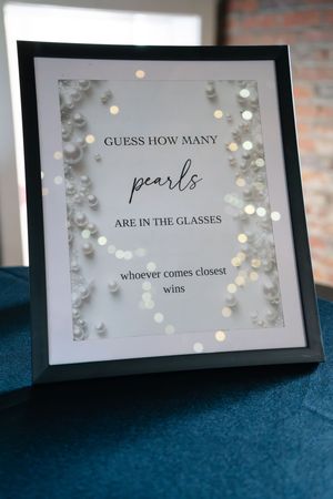 Framed pearl guessing game sign with fairy lights for a bridal shower party decoration.