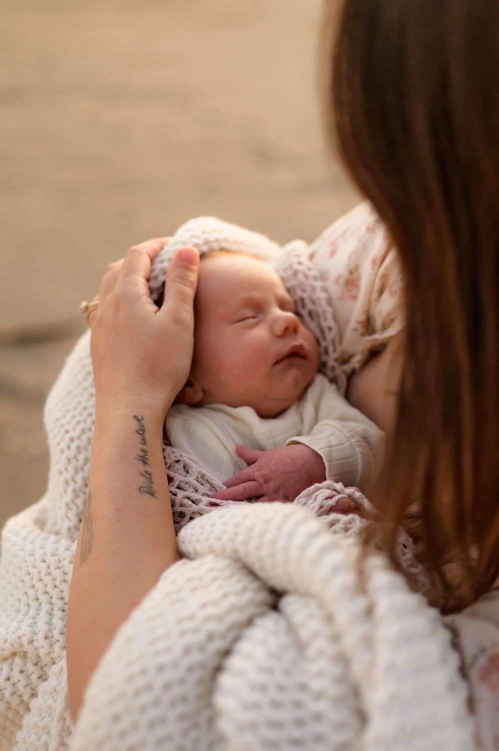 mother holding her newborn baby rubbing her face during beach newborn photoshoot in Ventura, captured by Ventura photographer