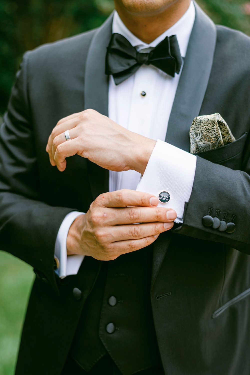 Close-up shots of groom adjusting cufflinks and bow tie in formal black tuxedo.