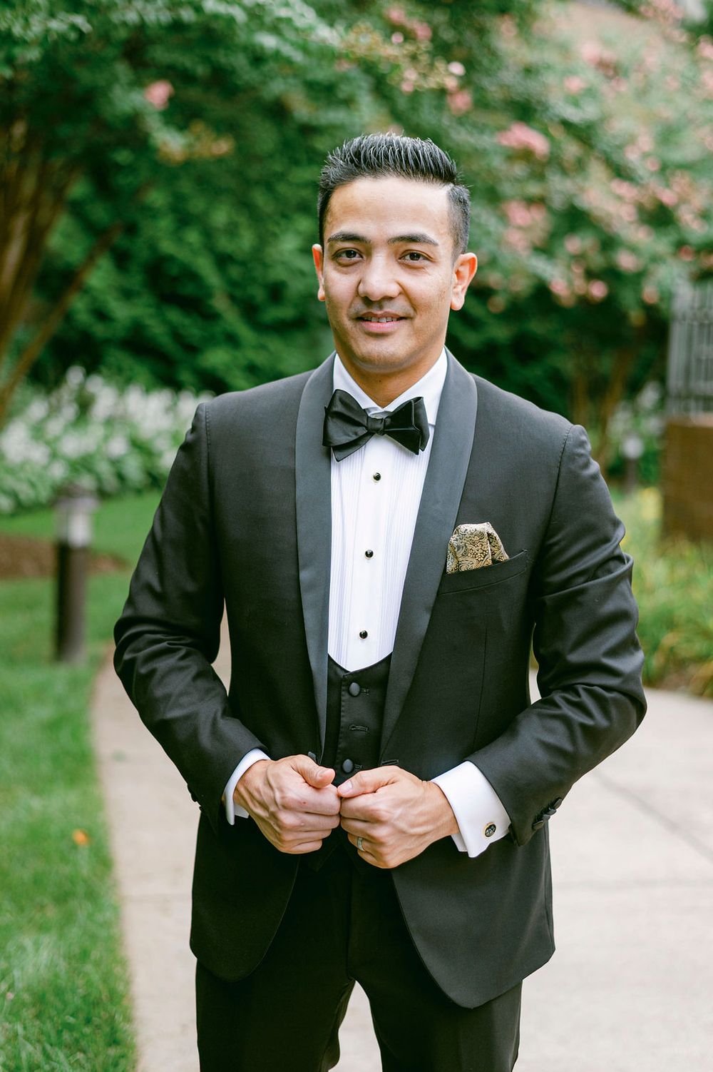 A sequence of photos showing a groom in a classic black tuxedo adjusting his bowtie outdoors.