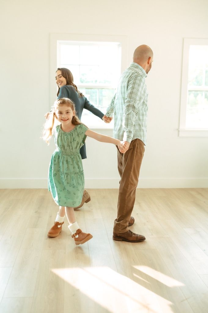 Playful dance sequence in a bright sunlit room with wooden floors.