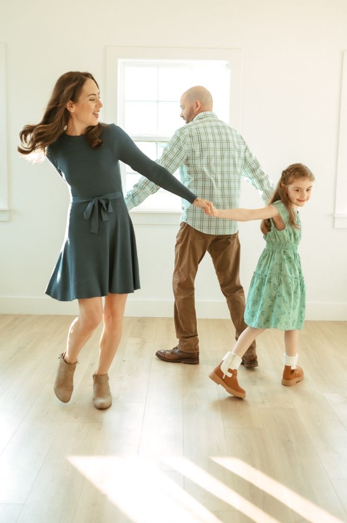 A sequence of playful dance movements captured in a bright white room with hardwood floors.