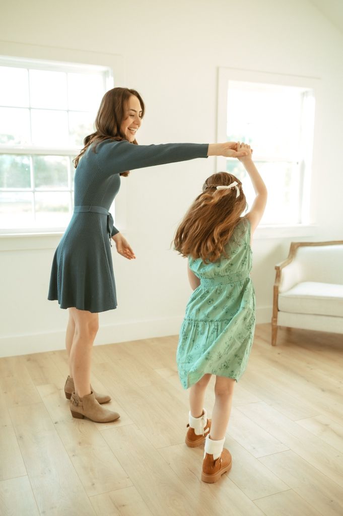 Dancing figures twirl and play in a bright white room with wooden flooring.
