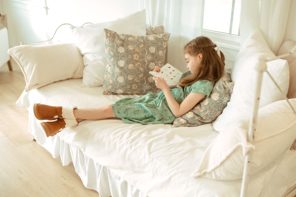 A family lounges together on a white couch in soft natural light.