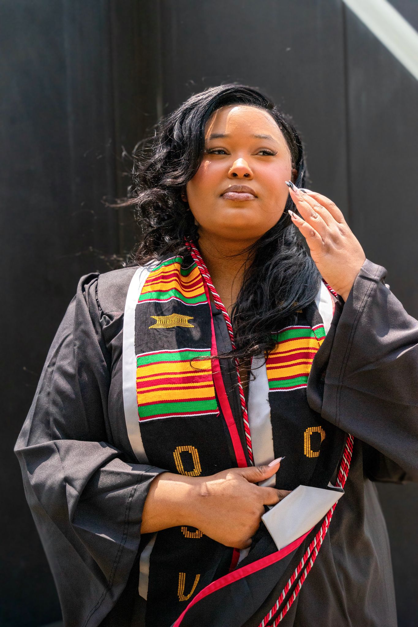Graduation photos featuring academic regalia with colorful kente stole against dark background.