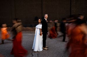 Motion-blurred wedding party creates artistic silhouettes against dark background.