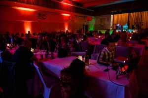 Wedding reception venue with red mood lighting and tables set for dinner celebration.
