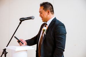 Professional speaker in a business suit gestures while presenting with a microphone at a corporate event.