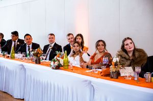 People seated at long banquet tables with white tablecloths during a formal dining event.