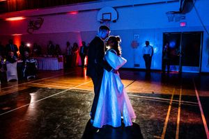Couple dancing in an elegant ballroom illuminated by dramatic blue and red lighting.
