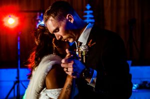 Romantic dance scene with red and blue lighting at evening wedding reception.