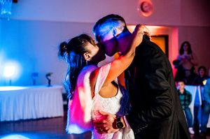 Wedding reception dance floor filled with guests dancing under colorful blue and purple lighting.