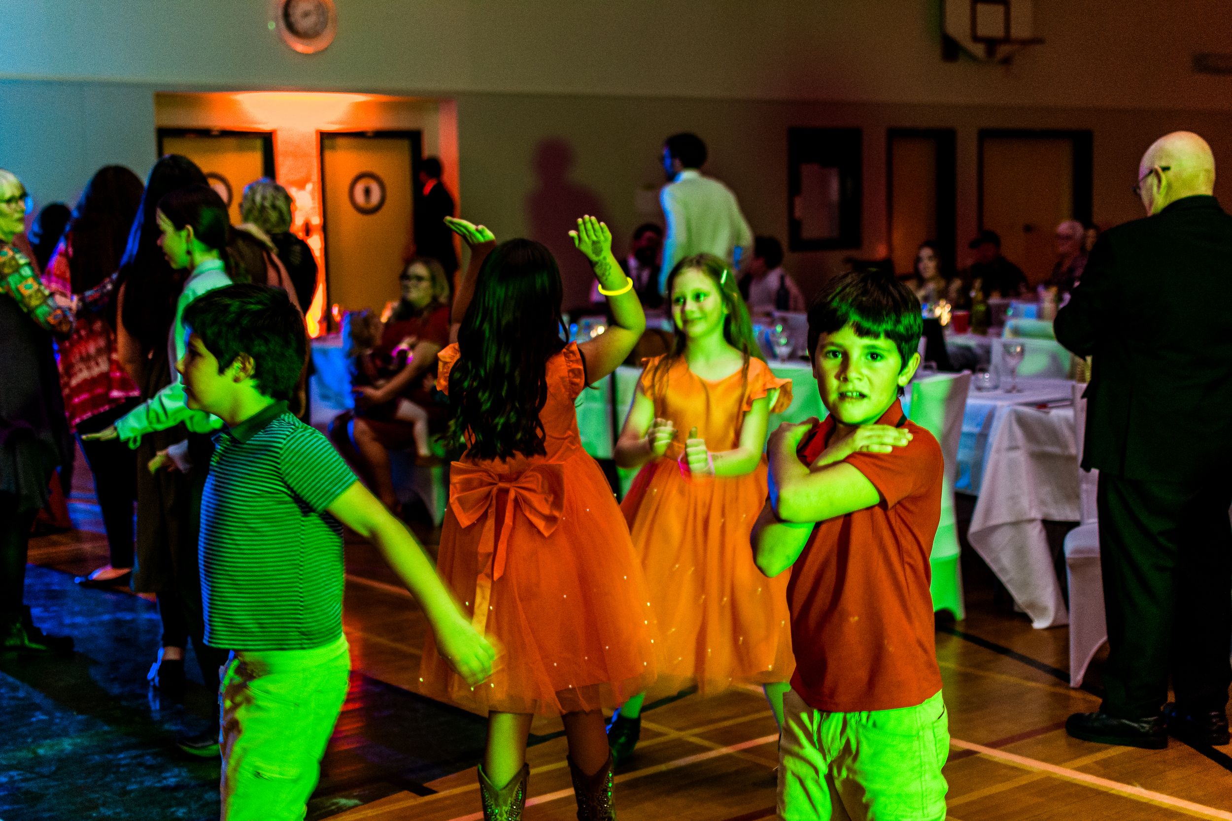 Dance party scene with green lighting effects illuminating guests on the dance floor at a wedding reception.