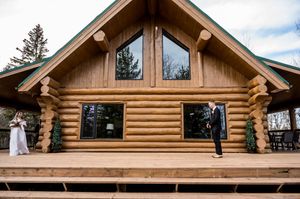 Rustic log cabin wedding venue with wooden deck and large windows.