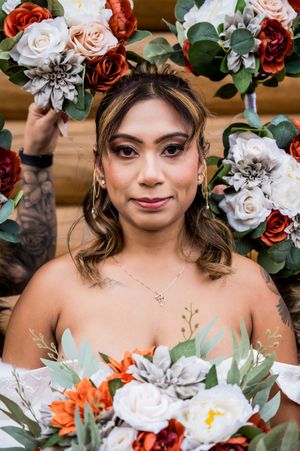 Wedding portrait featuring floral crown with red and blush roses against natural greenery.