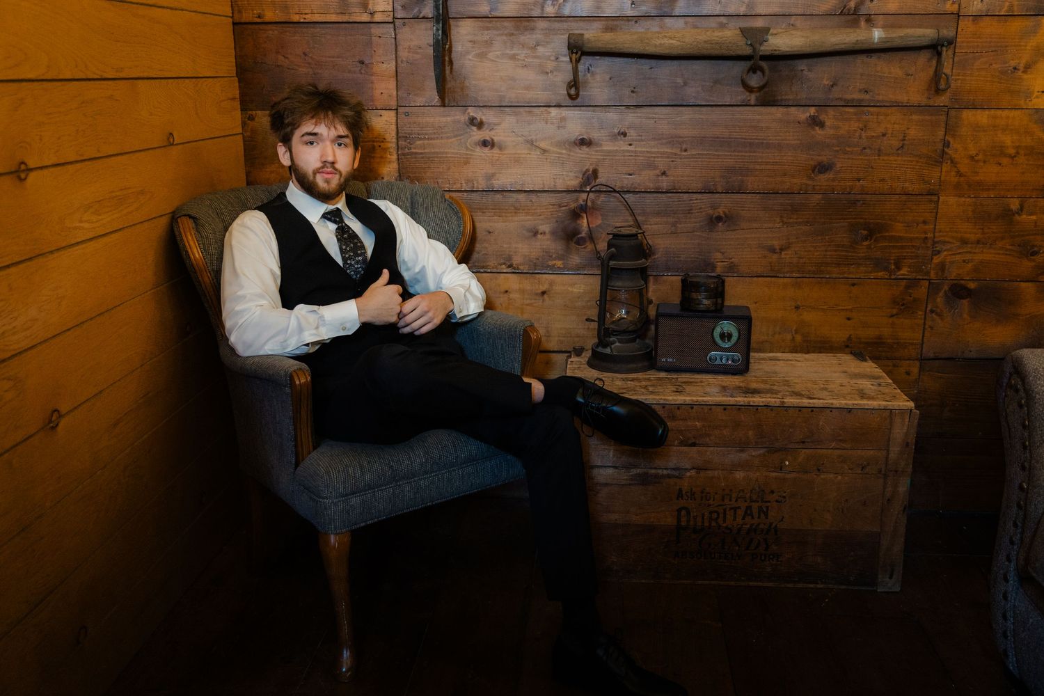 A rustic wooden wall serves as a backdrop for a professional portrait session in warm lighting.
