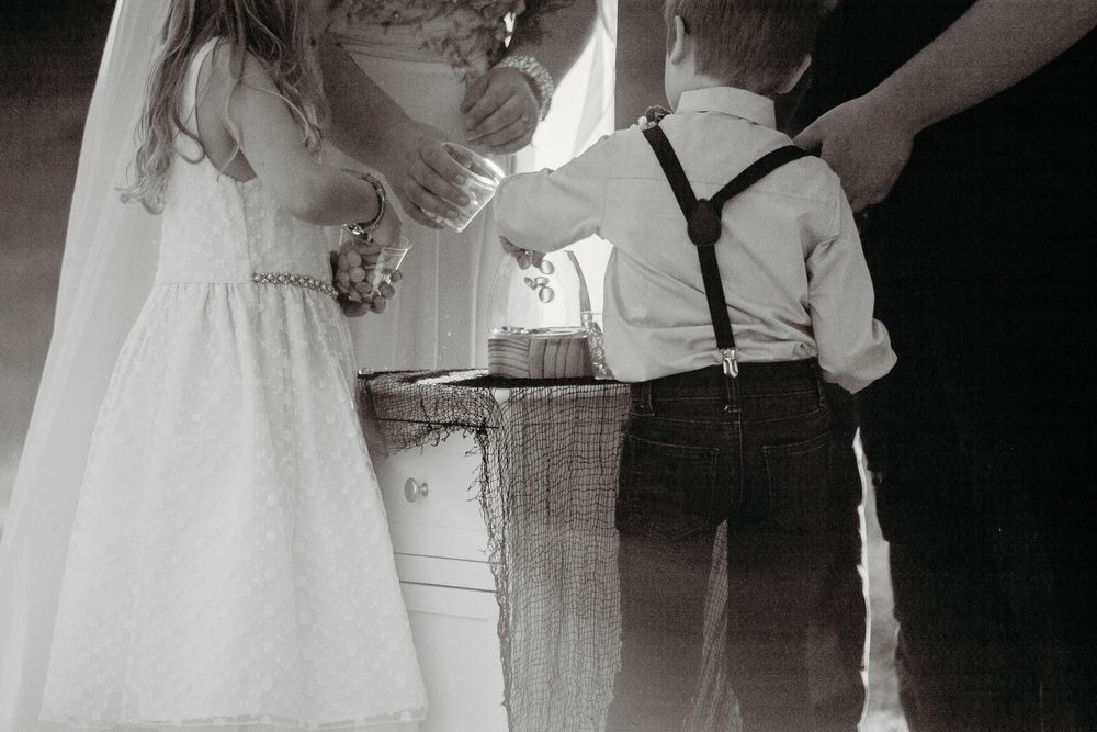 Black and white photo of child participating in wedding ring ceremony.