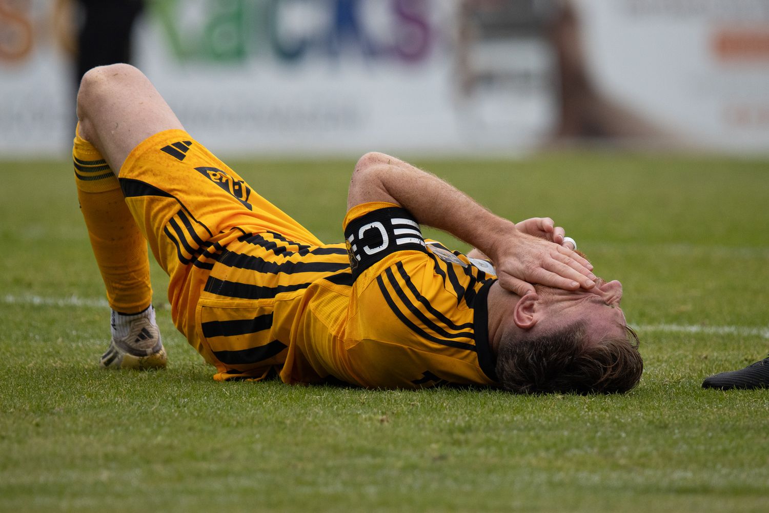 Multiple soccer players in yellow jerseys lay on the grass field in apparent defeat.