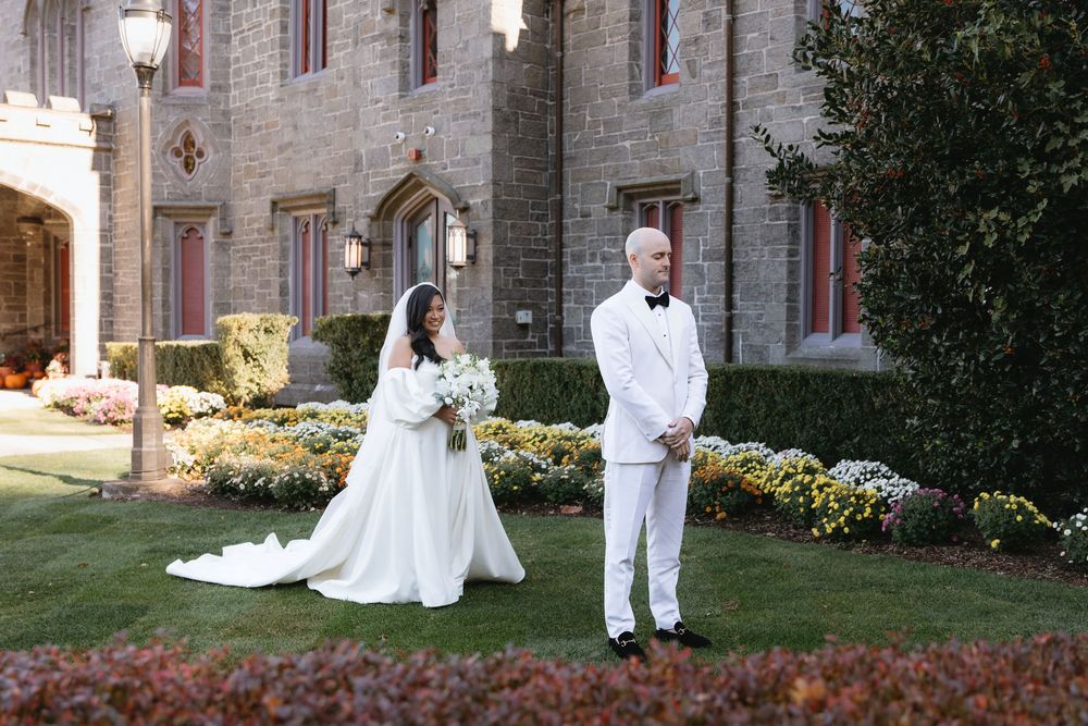 A couple in wedding attire walks together on a church lawn during their outdoor ceremony.