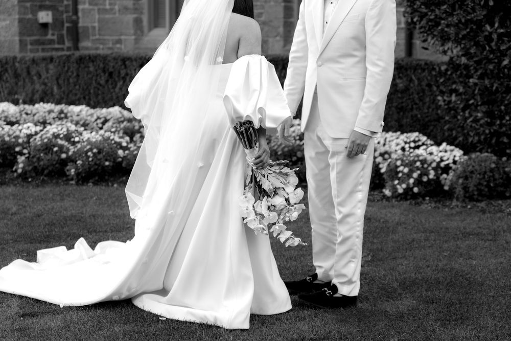 Bride and groom share a romantic moment on a garden path surrounded by lush greenery and flowers.