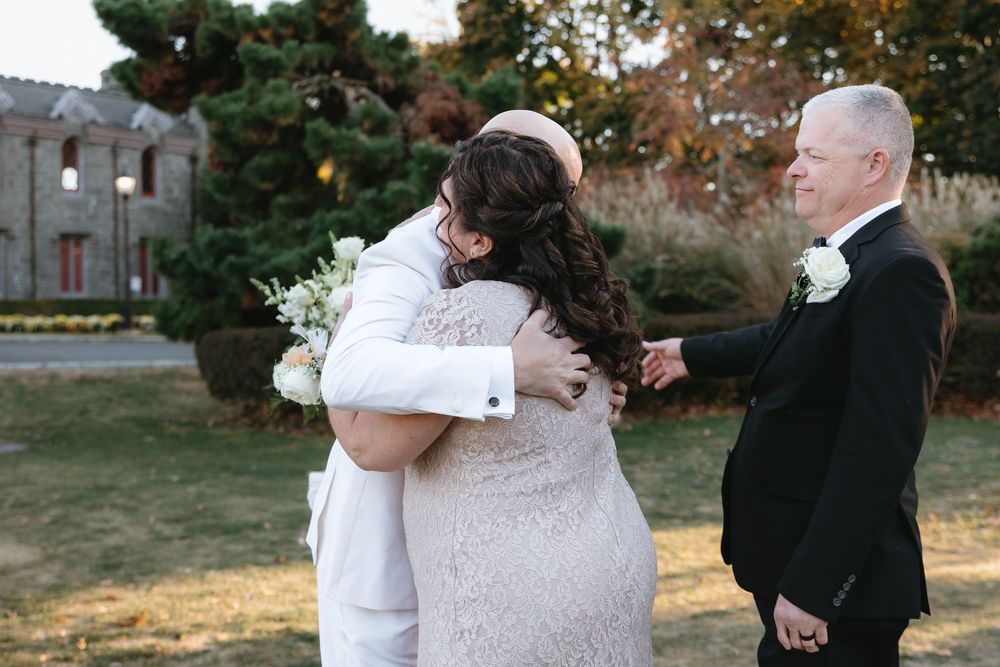 Romantic wedding ceremony moment with couple and officiant standing together outdoors at sunset.