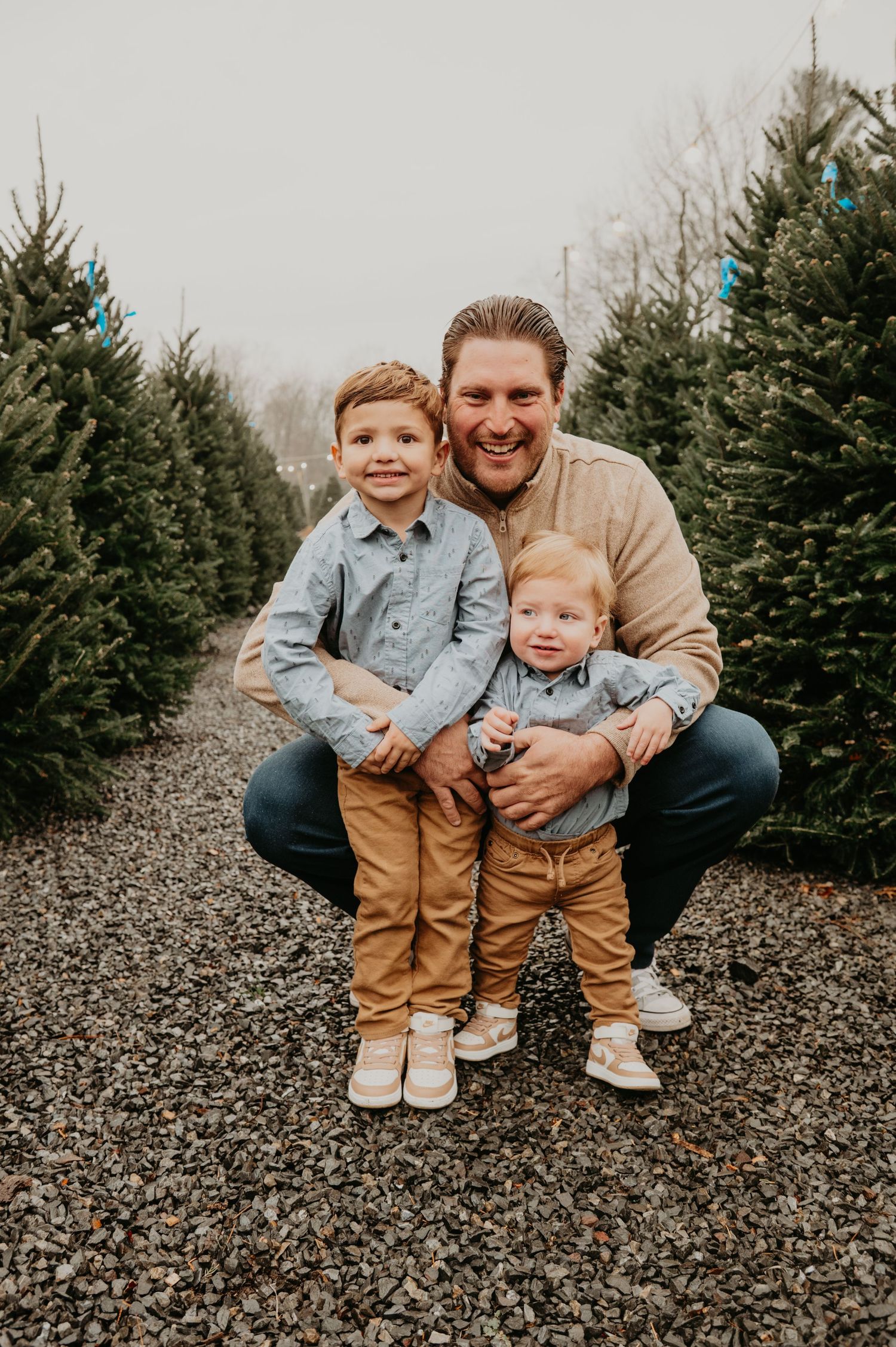 Family walking together through a Christmas tree farm in New Jersey, smiling and holding hands during a festive holiday photo session