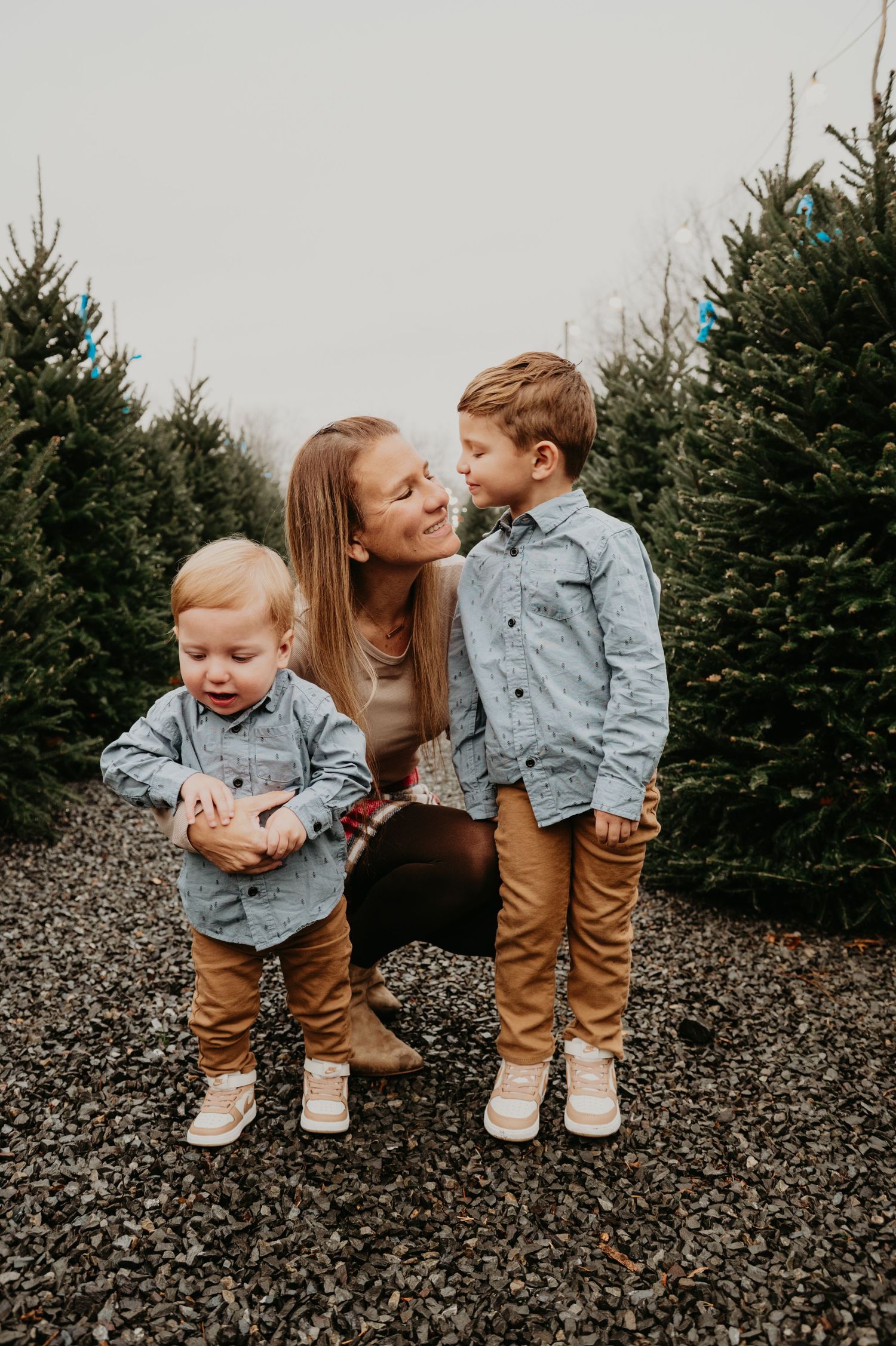 Family walking together through a Christmas tree farm in New Jersey, smiling and holding hands during a festive holiday photo session