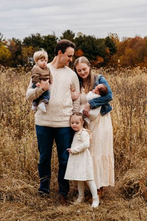 A family shares tender moments together in a golden autumn field during a lifestyle photoshoot.