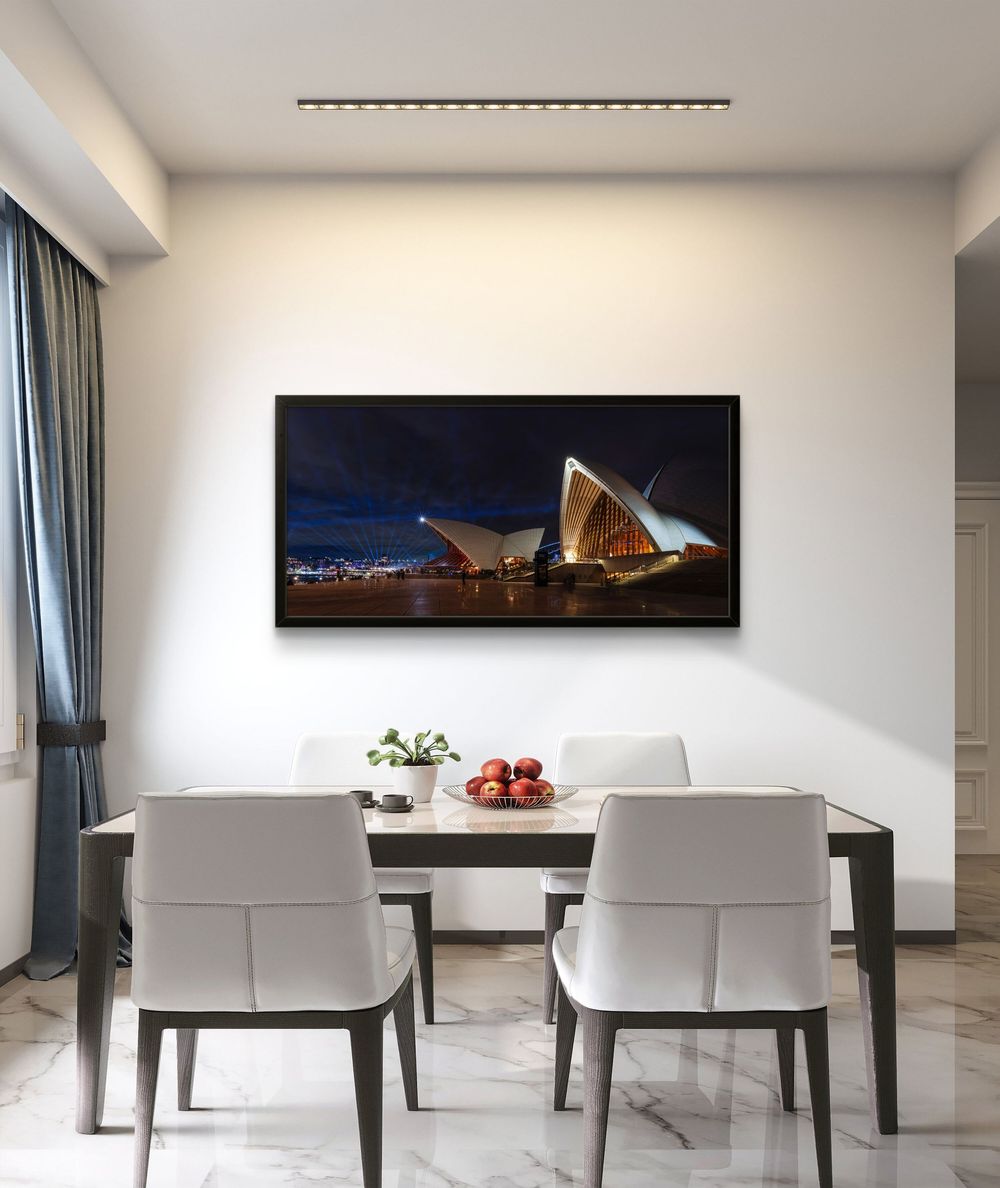 Framed panoramic print of Sydney Opera House at night displayed in a modern white dining room.