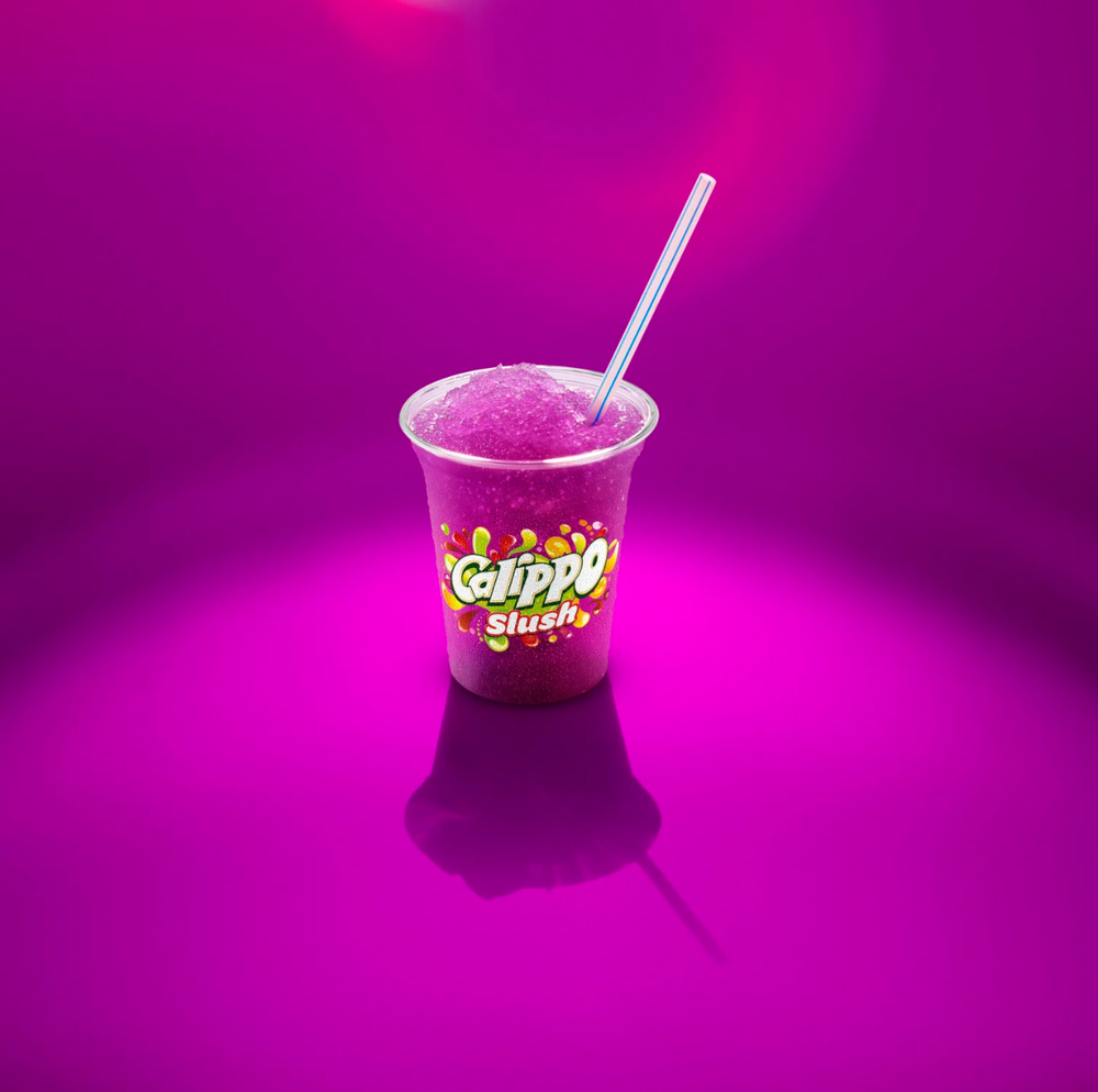 A dark purple beverage in a clear glass with a white straw against a vibrant magenta background.