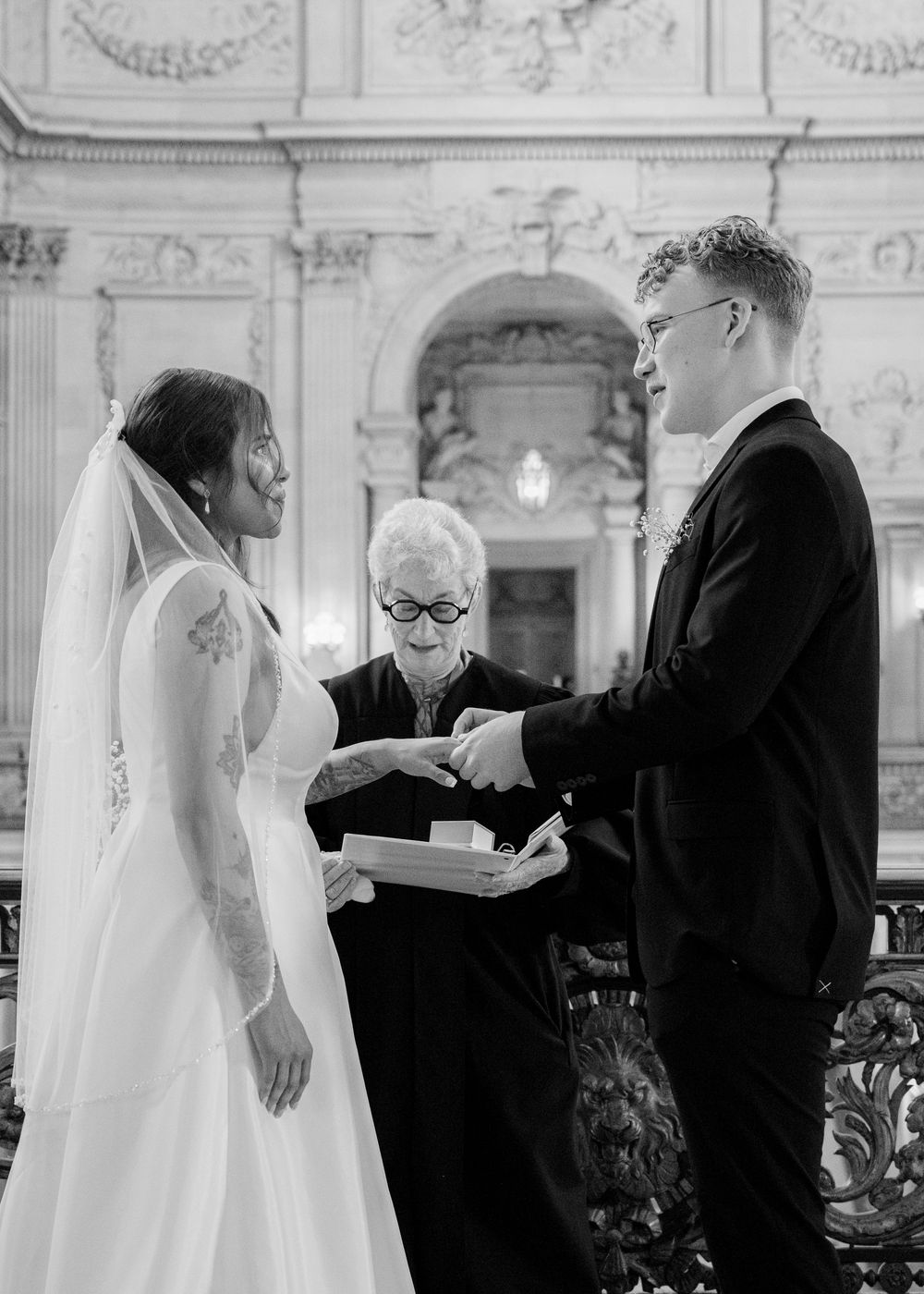 A wedding ceremony in progress inside a beautiful classical building with decorative moldings and columns.