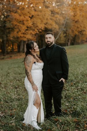 Wedding couple shares intimate moment in front of autumn trees.