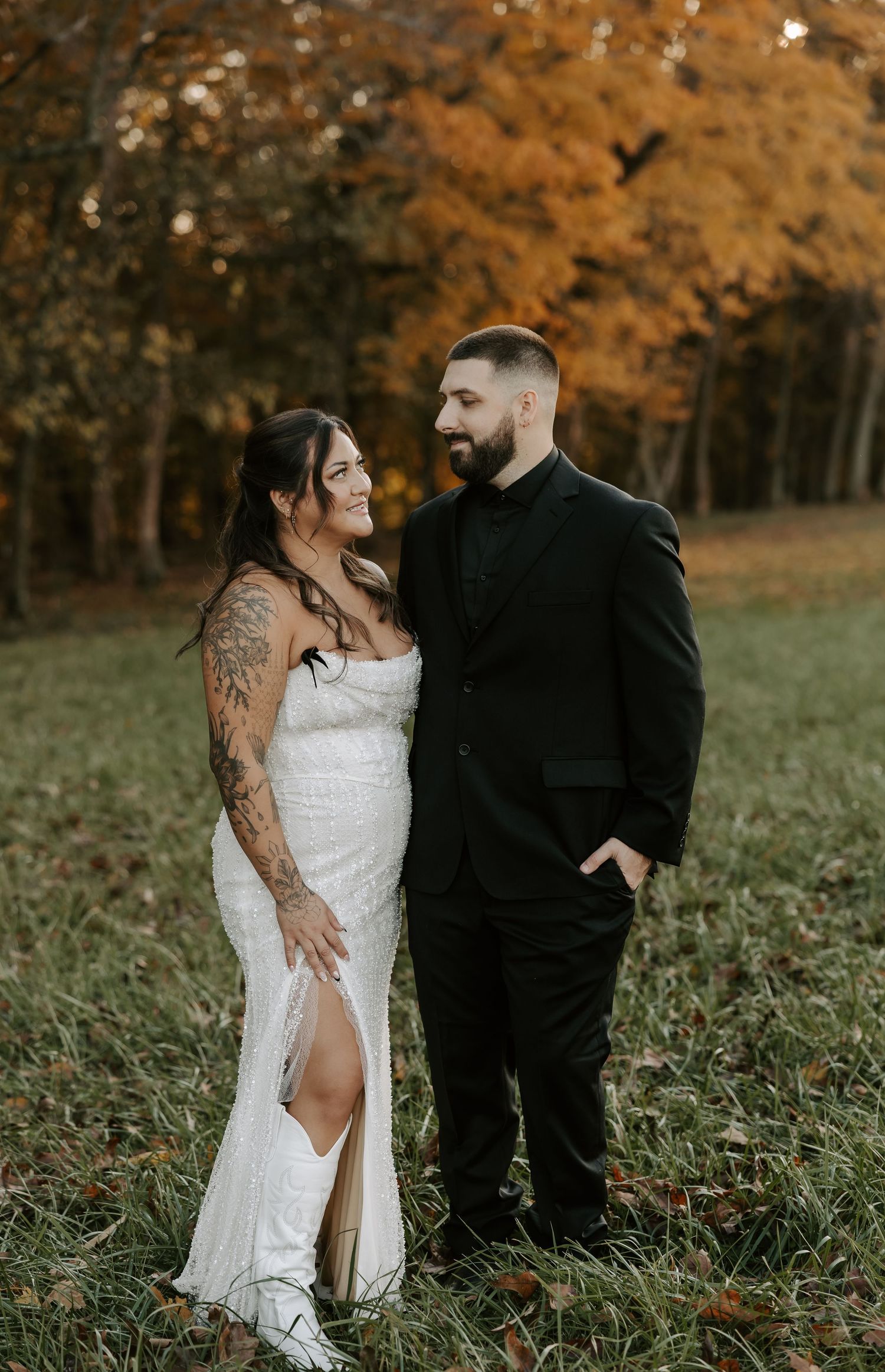 Newlyweds pose together against vibrant fall foliage in outdoor setting.