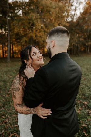 Intimate wedding moment captured in a field with autumn foliage creating a warm backdrop.