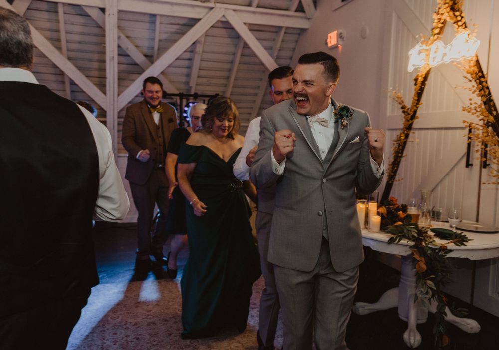 Wedding celebration in a rustic barn venue with exposed wooden beams and decorative lighting.