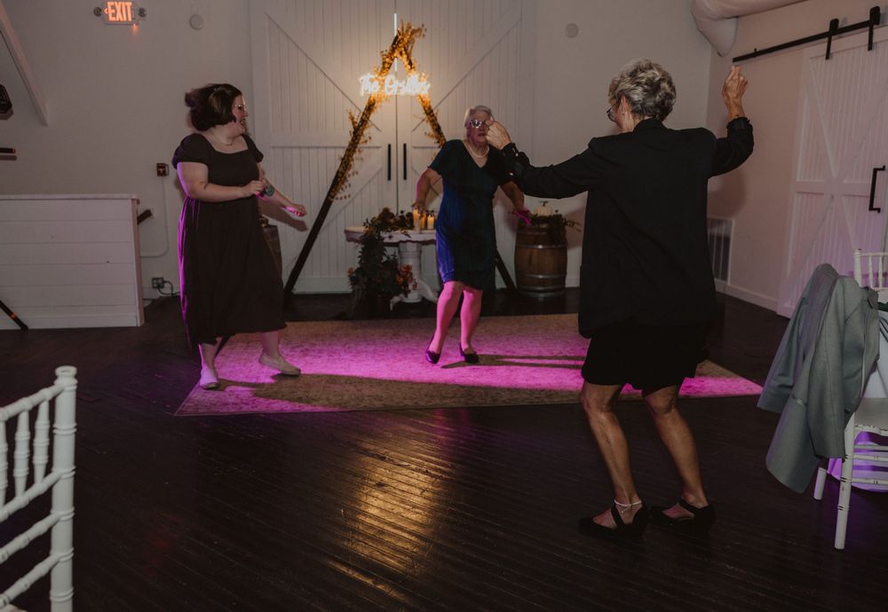 Wedding reception dance floor with purple mood lighting and white wooden chairs.