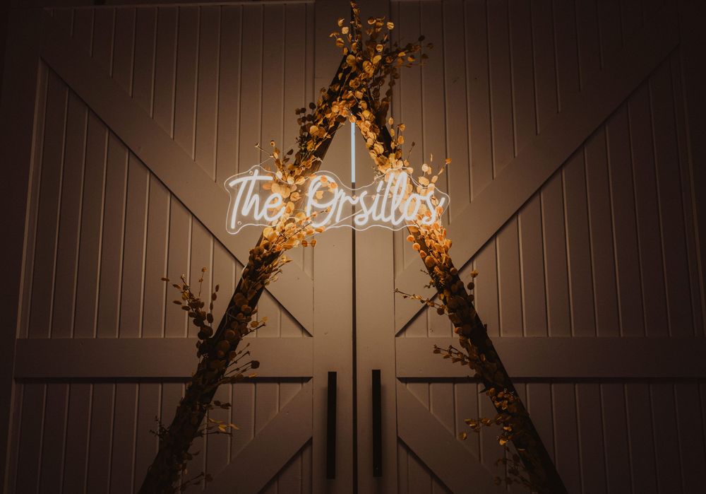 Rustic barn wedding venue interior with string lights and decorative branches on the wall.