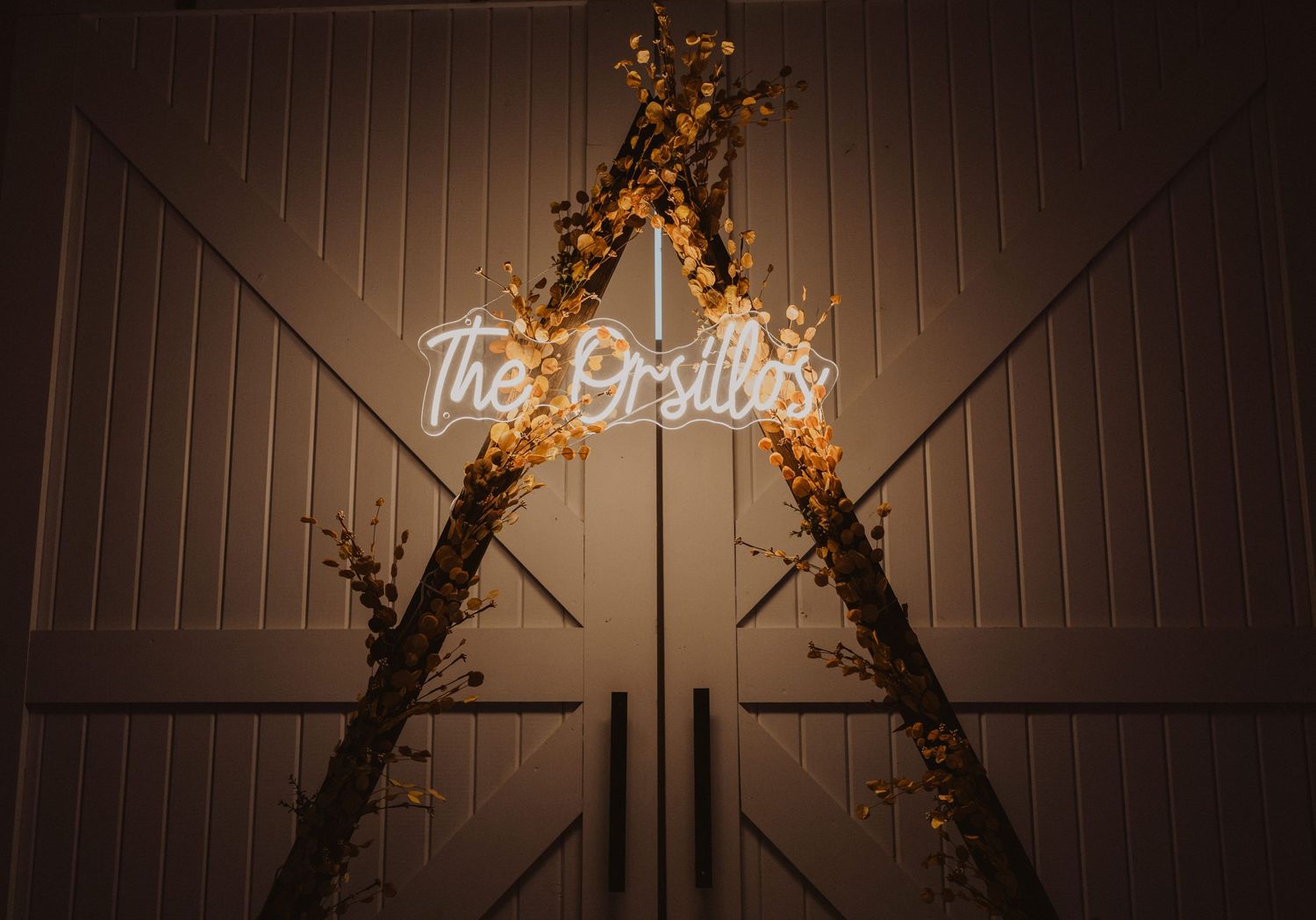 Rustic barn wedding venue interior with string lights and decorative branches on the wall.