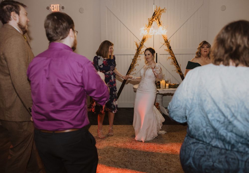 Wedding reception dance party in a rustic venue with mood lighting and wooden walls.
