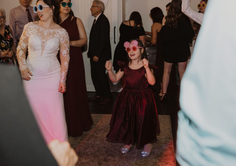 Two guests dancing at a wedding reception, with one wearing a pink dress and another in a burgundy dress.