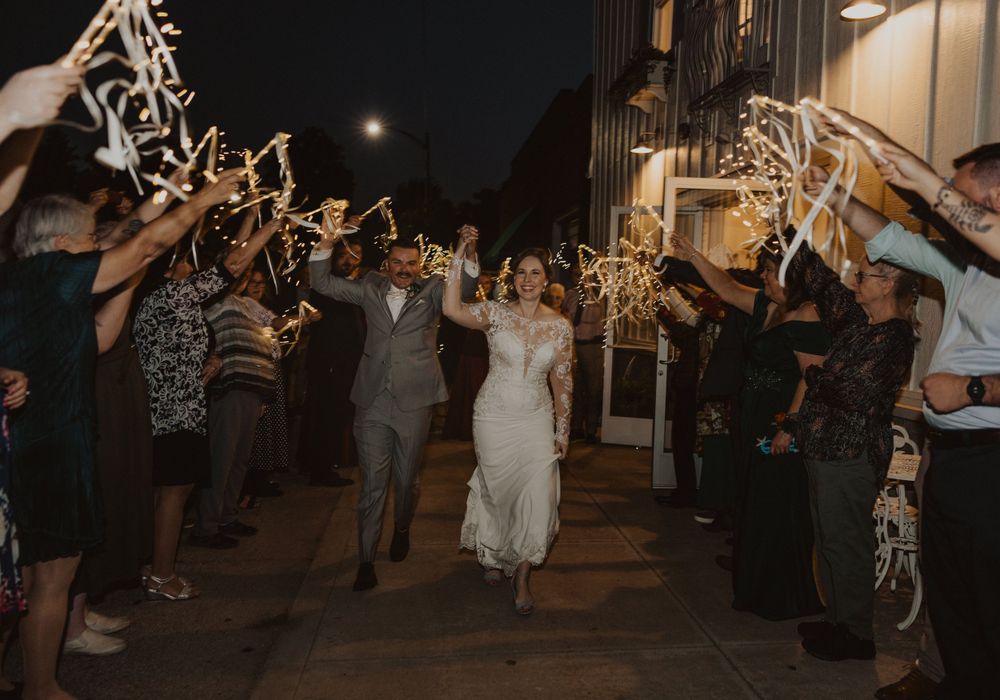 Guests line up with sparklers creating a magical nighttime wedding exit pathway.