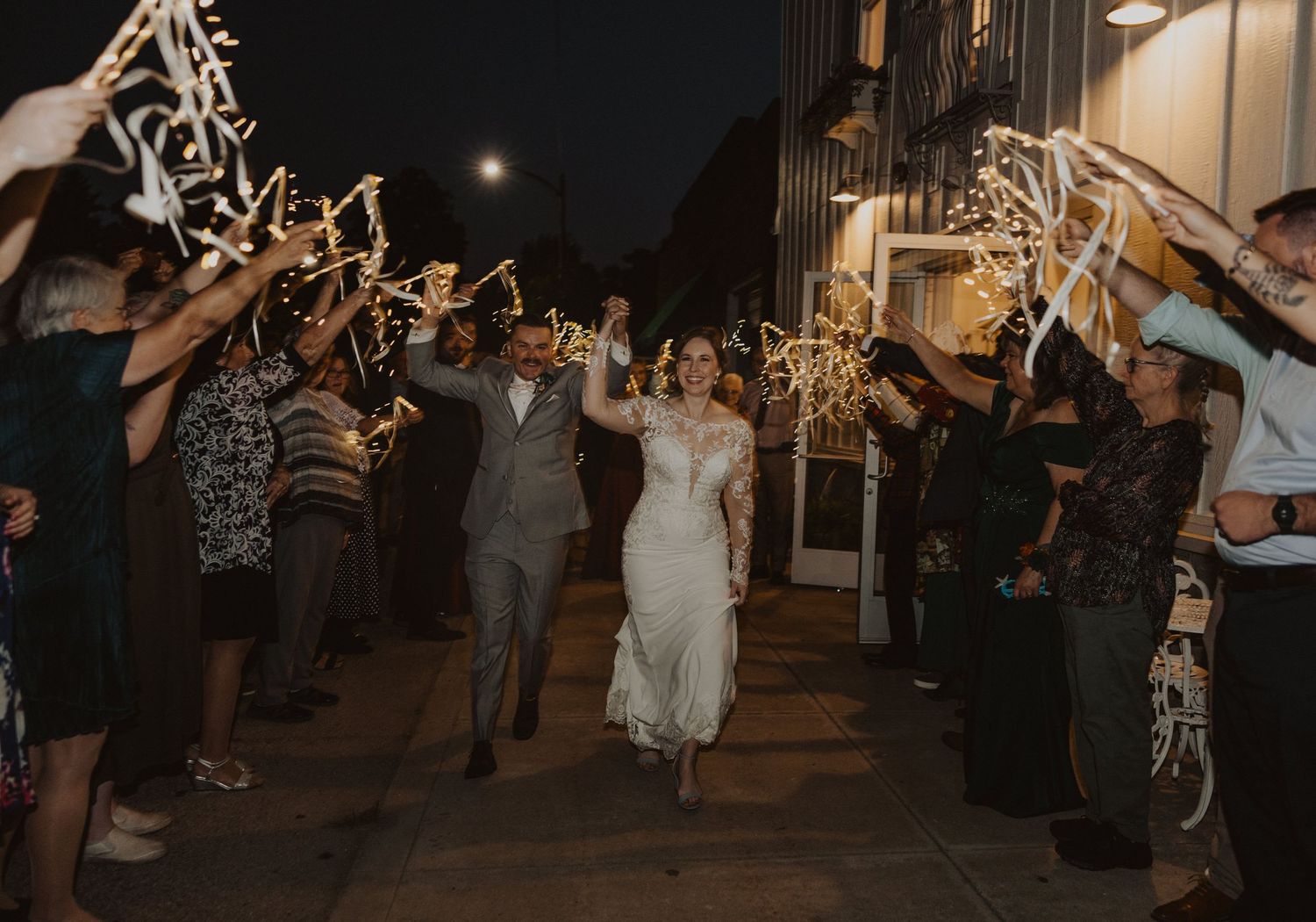 Guests line up with sparklers creating a magical nighttime wedding exit pathway.