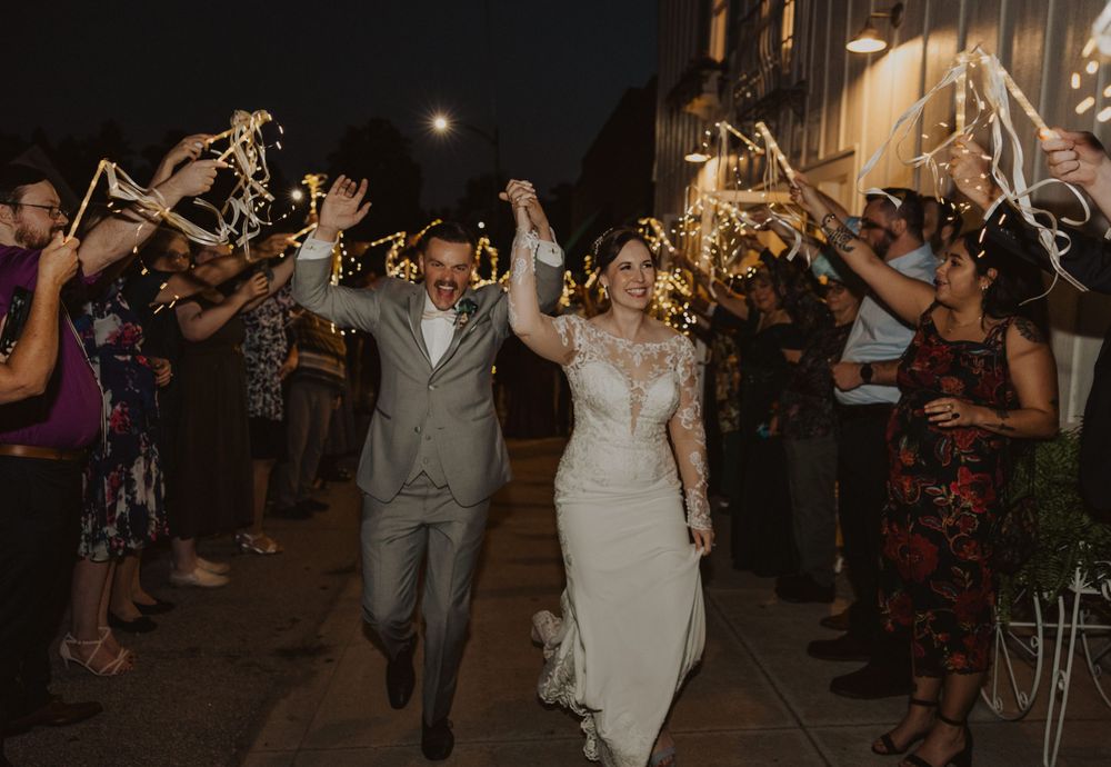 Newlyweds celebrate while walking through a sparkler-lit pathway during their evening reception exit.