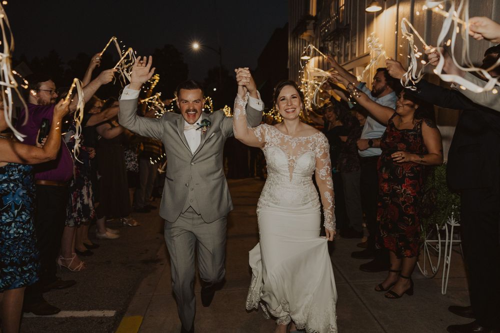 Wedding couple exits through a sparkler tunnel surrounded by celebrating guests.
