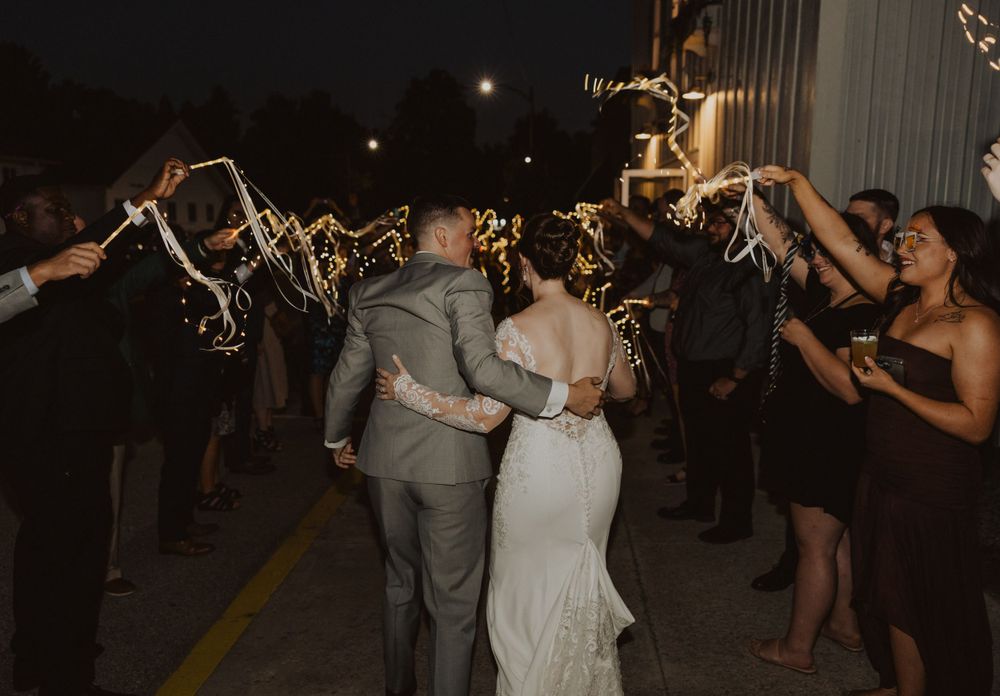 Wedding sparkler exit with couple walking through illuminated pathway at night.