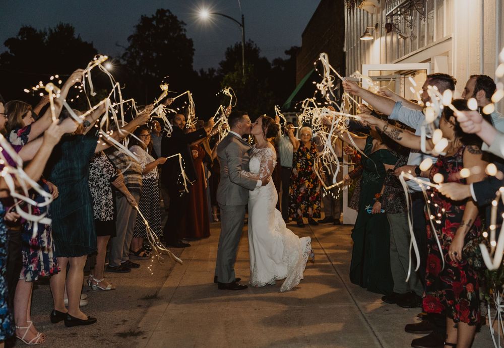 Wedding guests form a sparkler tunnel as couple shares romantic moment under the moonlit sky.