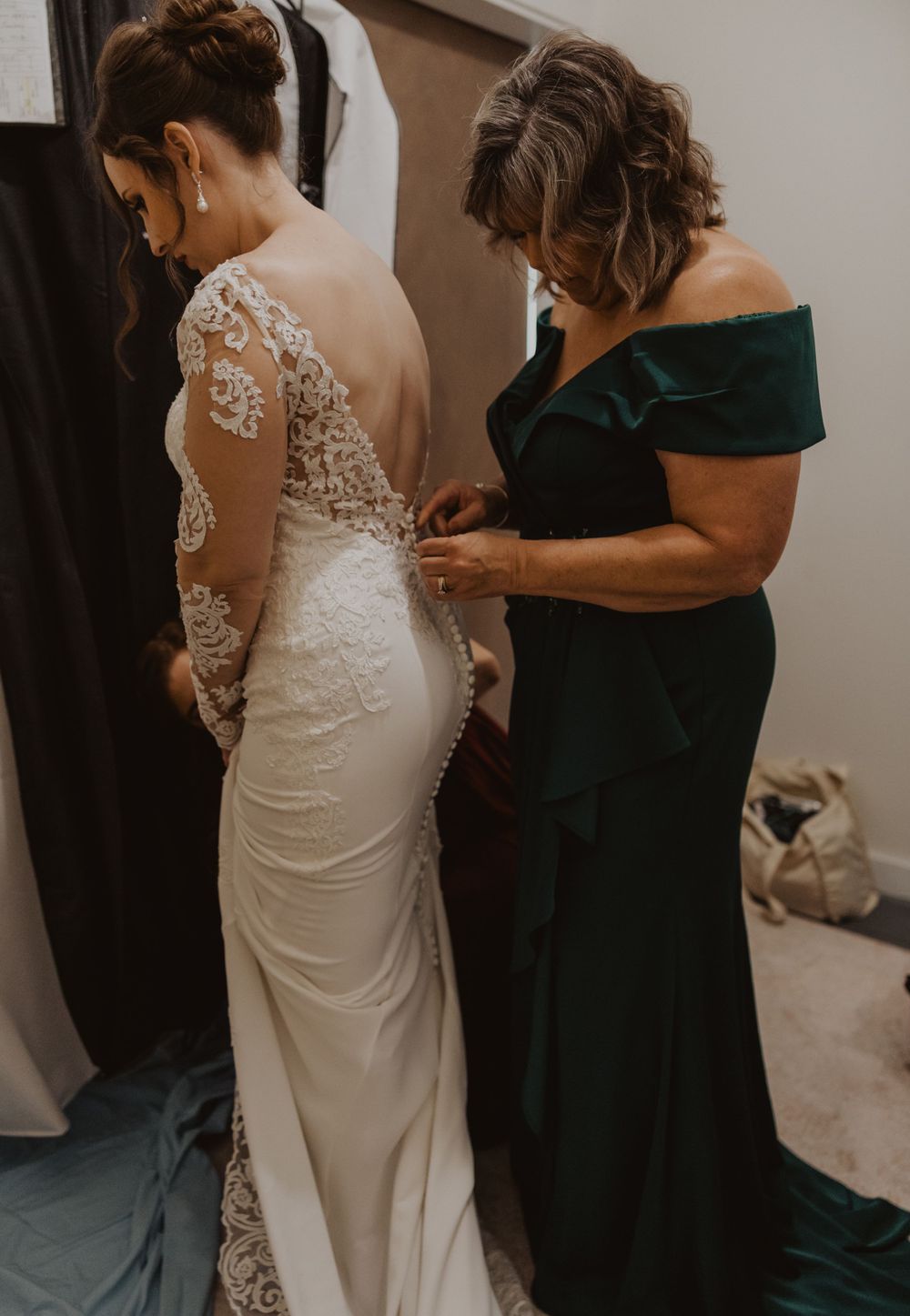 Wedding dress preparations showing detailed lace sleeves and elegant white gown fitting.
